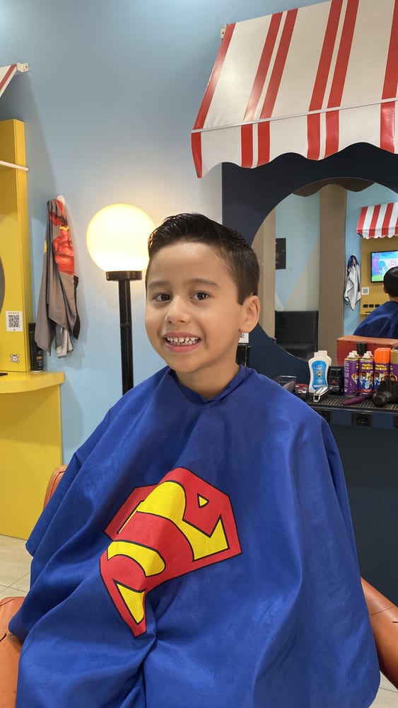 Menino sorrindo com capa de super-herói depois do corte